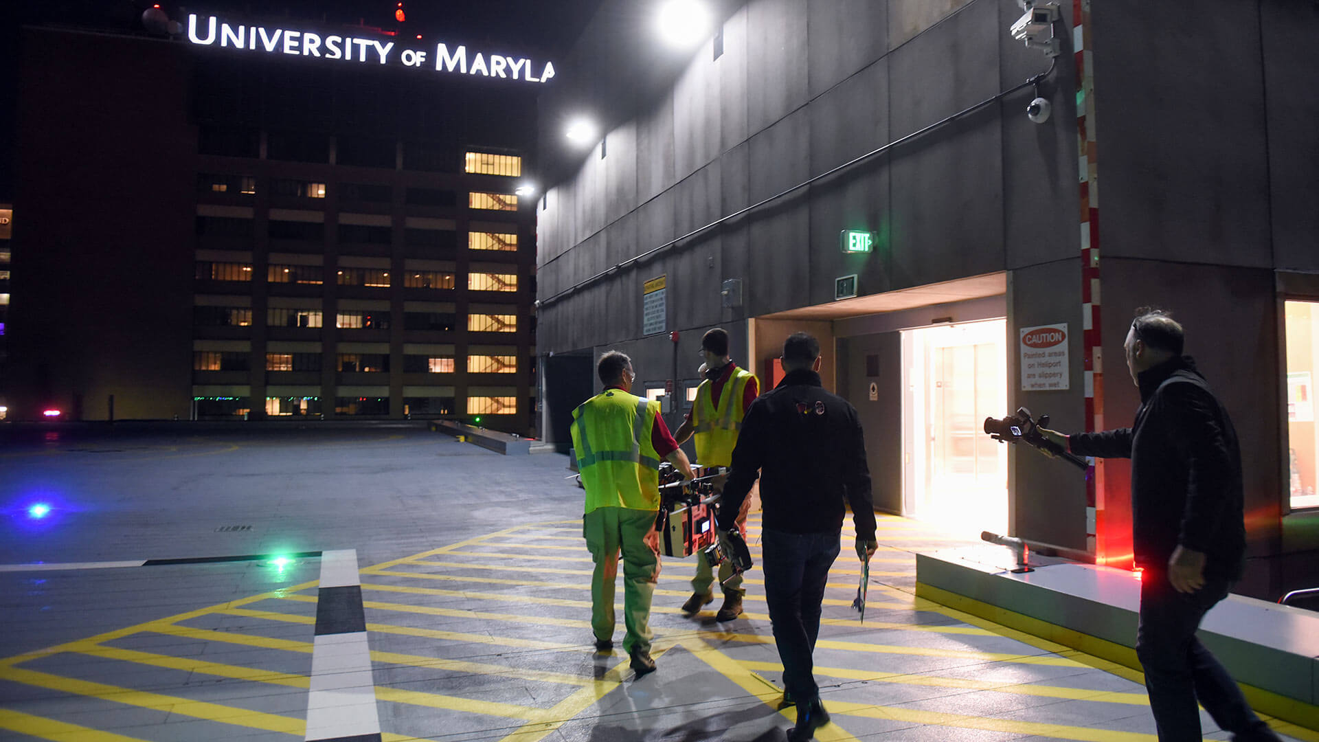 Test site personnel carry a drone on the roof of Shock Trauma.