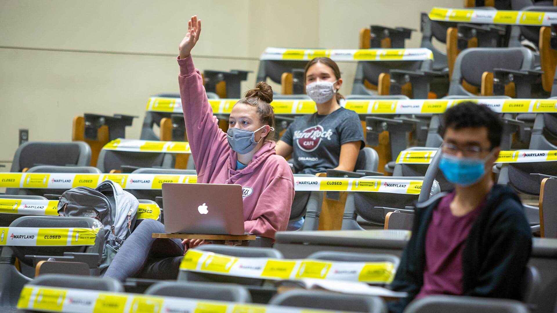 Masked student raises hand in class