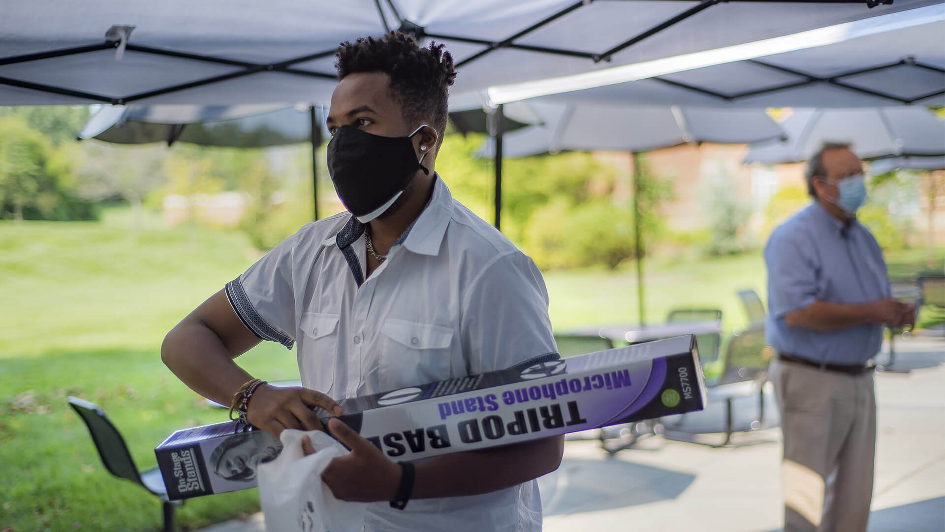 Student wearing a mask carries a tripod