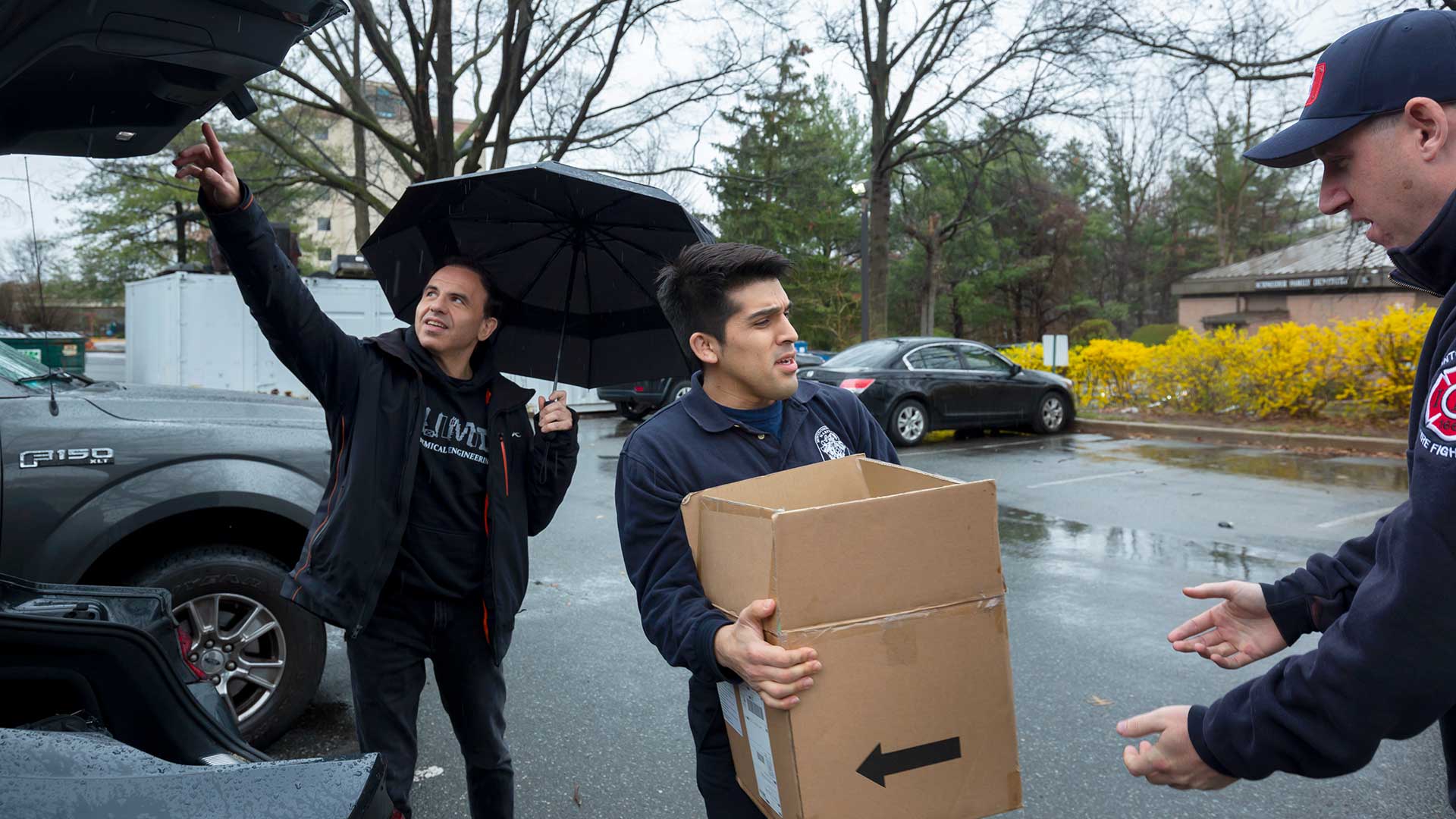 Firefighters unload boxes of hand sanitizer from the trunk of a car